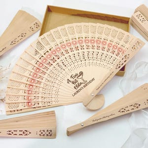 May include: Wooden hand fans with laser-cut designs and floral accents. The main fan has the text "A Tiny Bit Older, Lauren's Birthday". Other fans have the text "Thank you for celebrating with me".