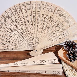 May include: A set of three wooden hand fans with a laser-cut design. The fans are decorated with the text "Class of 2025" and "Thanks for celebrating with us".