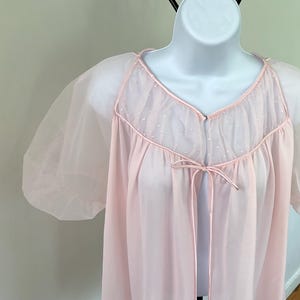 May include: A pale pink sheer robe with a lace trim and a tie at the waist.