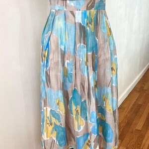 Puede incluir: Vestido sin mangas con estampado floral en tonos azules, amarillos y marrones. El vestido tiene un corpi&ntilde;o ajustado y una falda plisada. La tela parece ligera, adecuada para climas c&aacute;lidos. Aproximadamente 100 cm de largo.
