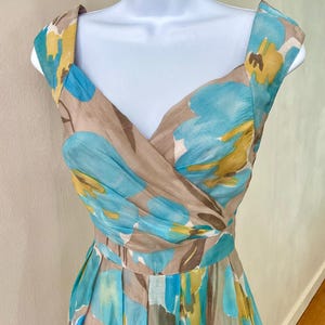 Puede incluir: Vestido sin mangas con estampado floral en tonos azules, amarillos y marrones. El vestido tiene un escote en V y una cintura entallada. La tela parece ligera, adecuada para climas c&aacute;lidos. El vestido mide unos 100 cm de largo.