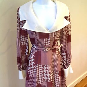 May include: A maroon and white checked dress with a large white collar and long sleeves. The dress has a belt and a fitted waist.