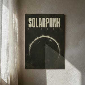 May include: A framed poster with the words "SOLARPUNK RISING" in a bold, sans-serif font. The poster features a dark, circular graphic resembling a solar eclipse. The color palette is primarily dark green and black, with off-white text.