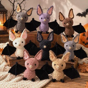 May include: A collection of eight crocheted bat plushies in various colors including gray, purple, brown, white, black, and tan. Each bat features large pointed ears with pink or tan inner details, small black eyes, a stitched nose, and black wings.
