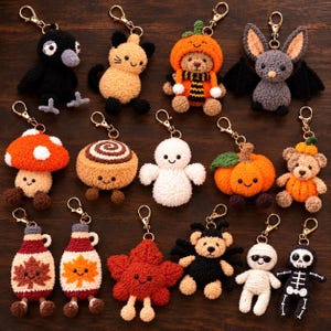 May include: A collection of fifteen crocheted keychains featuring various characters including a black bird, a tan cat, a bear in a pumpkin hat, a gray bat, a mushroom, a cinnamon roll, a ghost, a pumpkin, a bear in a pumpkin suit, two maple syrup bottles, a red leaf, a spider bear, a mummy, and a skeleton.