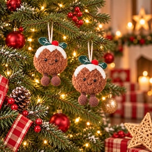 May include: Two brown crocheted Christmas pudding ornaments hanging from a tree. Each ornament features a white icing top, a small red berry, green leaves, black bead eyes, a stitched smile, and two small dangling brown feet.