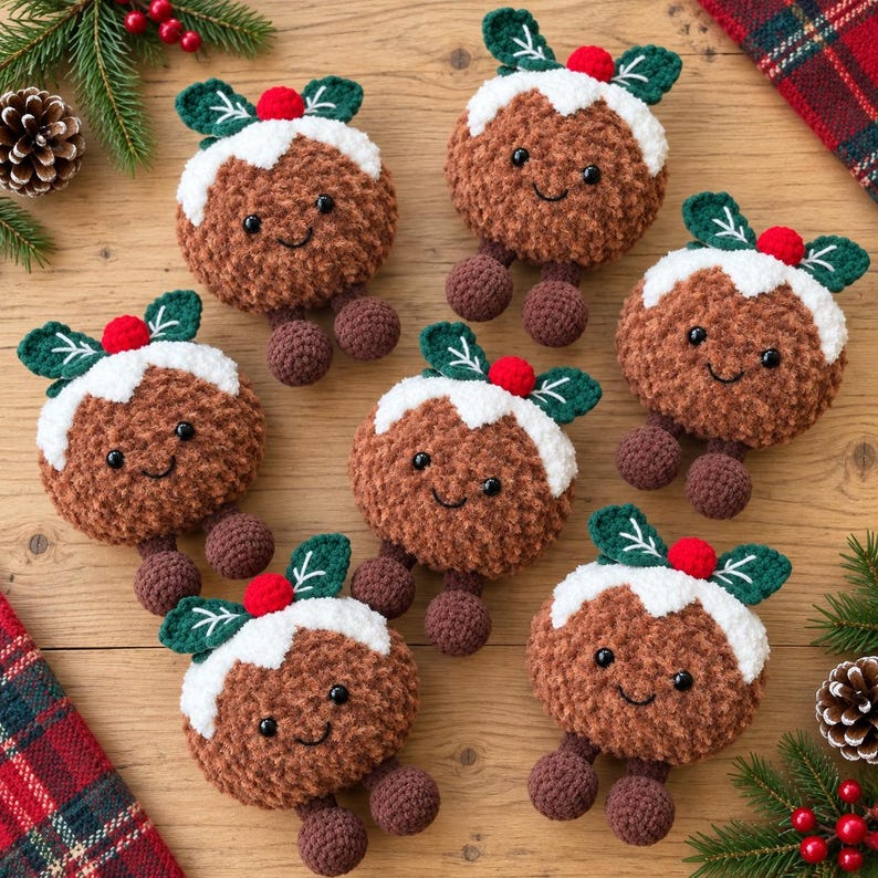 May include: A collection of six brown crocheted Christmas pudding ornaments with white icing tops, green leaves, and small red berries. Each plush figure features black safety eyes and a stitched smile, with two small round feet attached at the base.