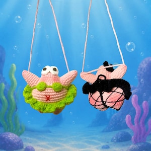 May include: Two crocheted pink starfish figures hanging by thin strings. The left figure wears a green bikini top and skirt. The right figure wears a black bikini top and a black fishnet skirt. Both figures have large white eyes and are suspended.