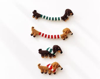 May include: Four crocheted dachshund ornaments. Two are long, stretched-out dogs wearing striped jumpers in green-white and red-white. Two are smaller, standing dachshunds wearing matching green-white and red-white striped jumpers.