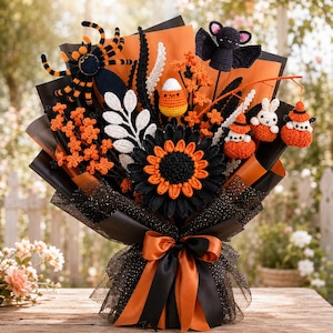 Puede incluir: Un ramo de ganchillo con temática de Halloween que incluye una araña negra y naranja, un murciélago negro, una figura de maíz dulce, un gran girasol negro y naranja y pequeñas figuras de conejos blancos, envuelto en papel negro y naranja.