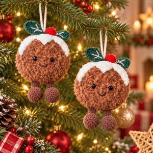May include: Two round, brown, fuzzy crochet ornaments shaped like Christmas puddings. Each features a white icing top, green leaves, a small red berry, black bead eyes, a stitched smile, and two dangling brown feet, all hanging from white strings.