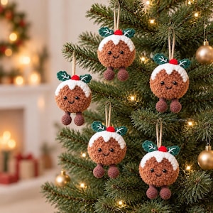 May include: Five round, brown, fuzzy crochet Christmas pudding ornaments hanging on a tree. Each ornament features a white icing top, green leaves, a red berry, two small black eyes, a stitched smile, and two dangling brown legs.