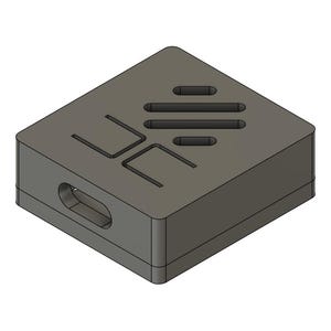 May include: A gray, rectangular block with a series of cut-out shapes on the top surface and a rounded hole on one side. The top features three horizontal slots and two stylized letter-like shapes. The object has a geometric, industrial design.