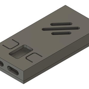 May include: A gray rectangular block with a series of cut-out shapes and slots. The top surface features three horizontal slots and a rectangular indentation. The front edge has two oval openings. The object is rendered in a 3D style.