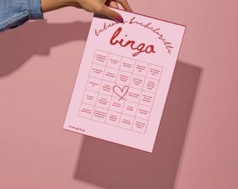 May include: A pink and red printable hen party bingo card with a heart in the centre. The card has 25 squares with different activities or events that might happen at a hen party.