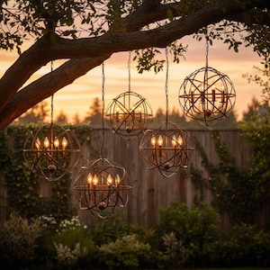 Puede incluir: Cinco candelabros esféricos para exteriores colgando de una rama de árbol. Cada candelabro tiene un diseño de jaula de metal con múltiples luces tipo vela en el interior. El fondo presenta una valla de madera, vegetación y una puesta de sol.