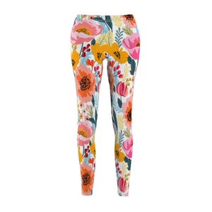 Pode incluir: Leggings florais com fundo branco e um padrão floral colorido. As leggings apresentam flores rosa, laranja, amarelas e verdes.