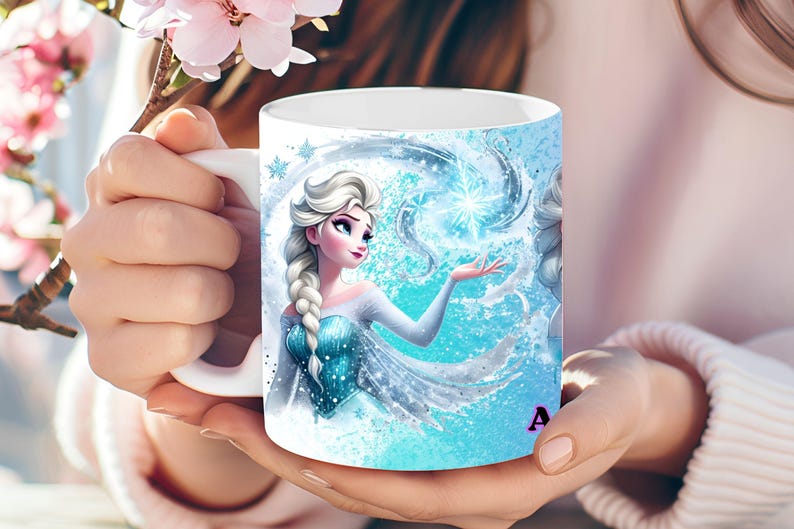 May include: White ceramic mug featuring a vibrant illustration of a character with long, braided white hair, wearing a blue dress, and surrounded by icy blue elements. The mug has a white handle and the letter "A" is visible on the side.