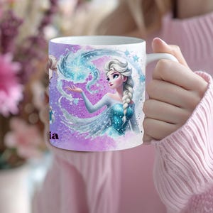 May include: White ceramic mug featuring a watercolor illustration of a princess with a long braid, wearing a blue dress, and surrounded by swirling blue and purple elements. The mug has the name "ia" printed on it.