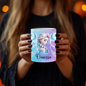 May include: A white ceramic mug with a gradient blue and purple background. The mug features a portrait of a woman with blonde hair and the name "Vanessa" in cursive. The design includes water and ice elements.