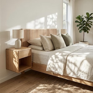 May include: A modern bedroom setup featuring a wooden bed frame with a slatted headboard. The bed is dressed with neutral-toned bedding and pillows. A floating wooden nightstand with a lamp sits beside the bed. A potted plant adds a touch of greenery.