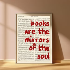 以下が含まれることがあります： ヴィンテージ本のページを背景にしたフレーム入りプリント。テキスト「books are the mirrors of the soul」は赤色です。白いフレームは、家庭やオフィスの装飾に適しています。