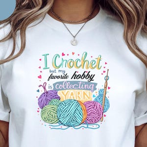 May include: White t-shirt with the text "I Crochet but my favorite hobby is collecting YARN" in a colorful design. The graphic includes yarn balls in purple, teal, green, and orange, along with a crochet hook.