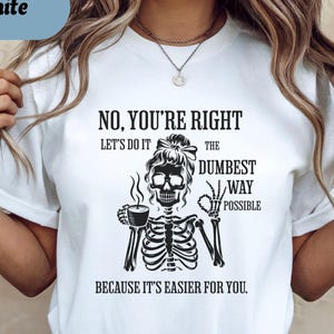 May include: White t-shirt with a black graphic of a skeleton holding a coffee cup and giving a thumbs up. The text on the shirt reads "NO, YOU'RE RIGHT, LET'S DO IT THE DUMBEST WAY POSSIBLE BECAUSE IT'S EASIER FOR YOU."