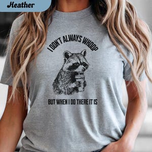 May include: Athletic Heather gray t-shirt with a graphic of a raccoon holding a drink. The text reads "I DON'T ALWAYS WHOOP BUT WHEN I DO THERE IT IS".