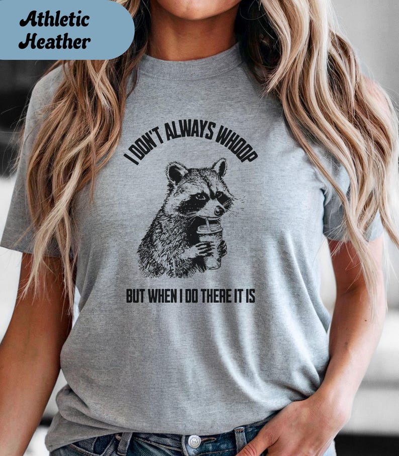 May include: Athletic Heather gray t-shirt with a graphic of a raccoon holding a drink. The text reads "I DON'T ALWAYS WHOOP BUT WHEN I DO THERE IT IS".