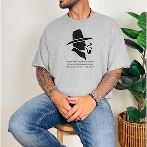 May include: A gray t-shirt with a black silhouette of a man wearing a hat and smoking a pipe. The text on the shirt reads: "A pipe gives a wise man time to think and a fool something to stick in his mouth." - C.S. Lewis