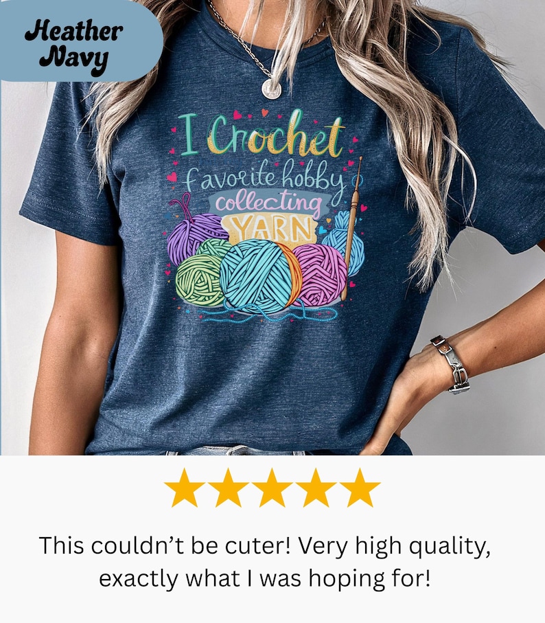 May include: Heather navy t-shirt with the text "I Crochet favorite hobby collecting YARN" and colorful yarn balls. The shirt features a crew neck and short sleeves. The design includes a crochet hook and the word "YARN".