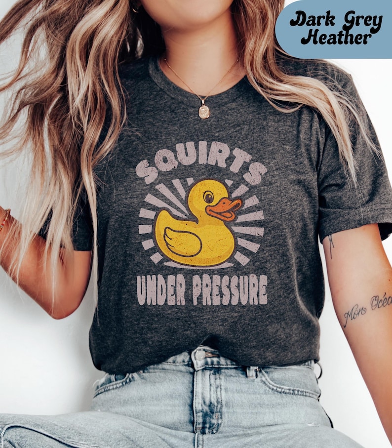 May include: A dark gray heather t-shirt with a yellow rubber ducky graphic and the text 'Squirts Under Pressure'.