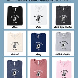 May include: A collection of Bella Canvas 3001 t-shirts in various colors, including black, white, and navy. Each shirt features the phrase "It Depends" with a raccoon graphic and "- HR" below. The shirts are displayed with a necklace.