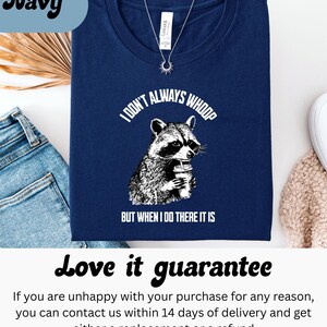 May include: Navy blue t-shirt with a graphic of a raccoon holding a cup, and the text "I DON'T ALWAYS WHOOP BUT WHEN I DO THERE IT IS". The shirt is next to a pair of blue jeans.