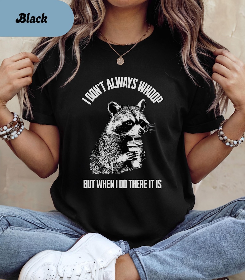 May include: Black t-shirt featuring a raccoon graphic holding a beverage. The text "I DON'T ALWAYS WHOOP BUT WHEN I DO THERE IT IS" is printed above and below the raccoon illustration. The shirt is a crew neck.