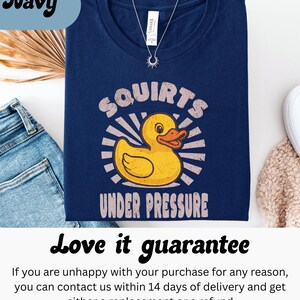 以下が含まれることがあります： 黄色いアヒルのグラフィックと「Squirts Under Pressure」の文字が入ったネイビーブルーのTシャツ。柔らかい素材で作られており、普段使いに最適です。