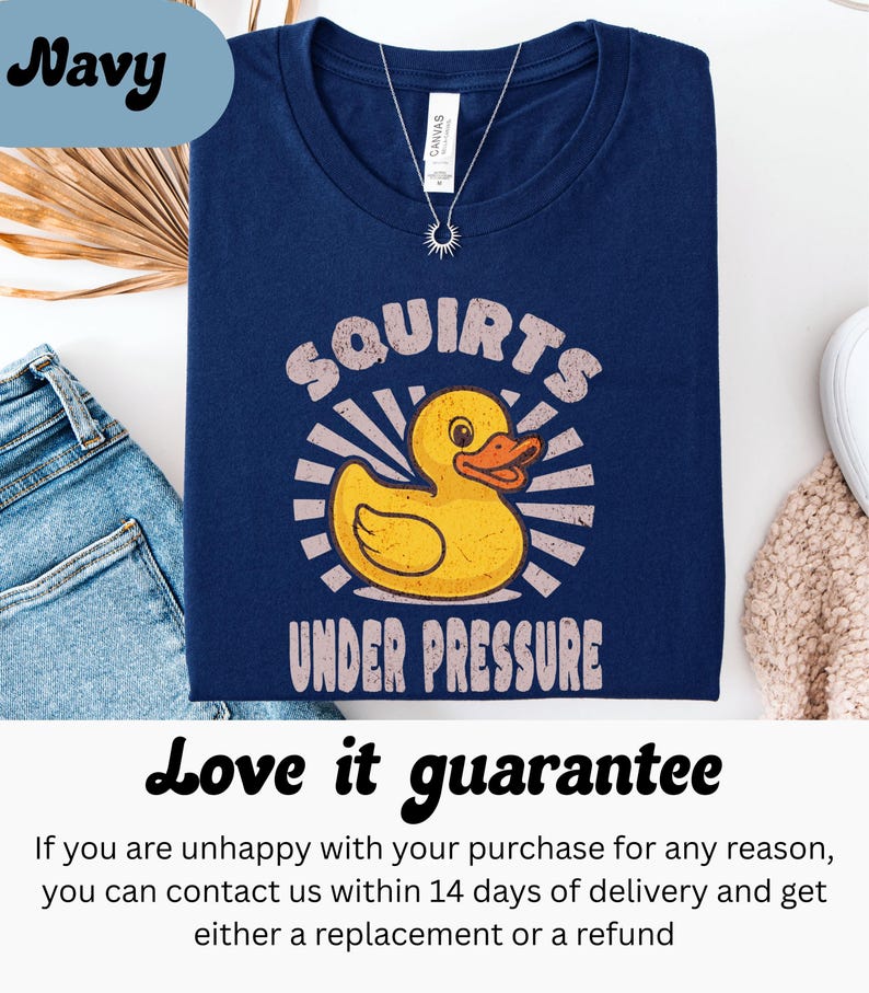 以下が含まれることがあります： 黄色いアヒルのグラフィックと「Squirts Under Pressure」の文字が入ったネイビーブルーのTシャツ。柔らかい素材で作られており、普段使いに最適です。