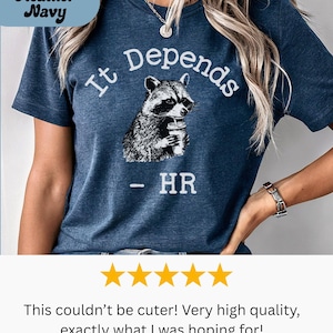 May include: Heather Navy t-shirt with the text "It Depends" and a raccoon graphic holding a drink. Below the graphic is "- HR". The shirt is a dark blue color.