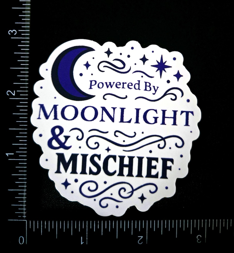 May include: A white sticker with a scalloped edge, featuring the text "Powered By Moonlight & Mischief" in navy blue. The design includes a crescent moon, stars, and decorative swirls. The sticker is on a black background.