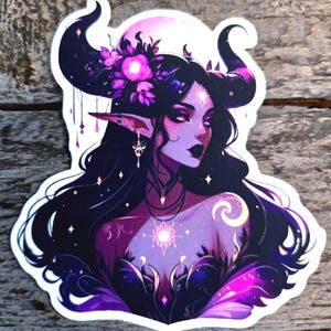May include: A die-cut sticker featuring a fantasy character with long dark hair, large curved horns, and pointed ears. The character has purple skin, wears a floral headpiece, and is adorned with glowing star-like symbols and jewelry.