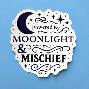 May include: A white sticker with a scalloped edge, featuring the text "Powered By Moonlight & Mischief" in a dark blue font. The design includes a crescent moon, stars, and decorative swirls on a light blue background.