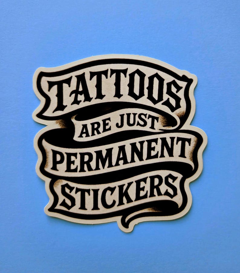 May include: A die-cut sticker featuring a black and cream-colored banner design with the text TATTOOS ARE JUST PERMANENT STICKERS in a bold, stylized serif font. The graphic has a vintage-inspired aesthetic with dark shading and curved edges.