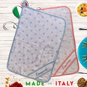 Può includere: Due asciugamani con cappuccio per bambini. Uno è azzurro con cuori blu e un bordo blu, l'altro è rosa con un bordo rosa. L'asciugamano blu ha ricamato il nome "Emanuele". L'asciugamano rosa ha ricamato il nome "Ginevra". Fatto in Italia.