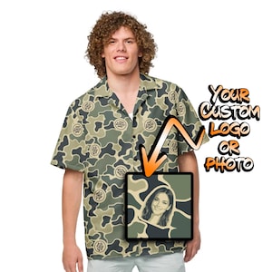 May include: A short-sleeved button-down shirt featuring a green and tan camouflage pattern with repeating circular logo placeholders. The shirt includes a graphic overlay with an orange arrow pointing to a square frame containing a portrait photo.
