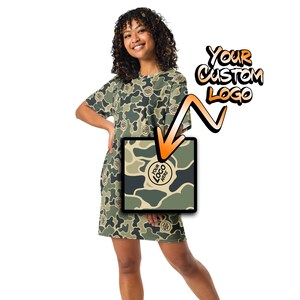 May include: A camouflage print t-shirt dress with a round logo that says "Your Logo Here". The dress is shown on a model. The text "Your Custom Logo" is written in orange and black on the right side of the image.