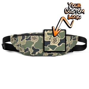 May include: A camouflage fanny pack with a black adjustable strap. The pack has a zipper closure and a small patch on the front that says "YOUR LOGO HERE".