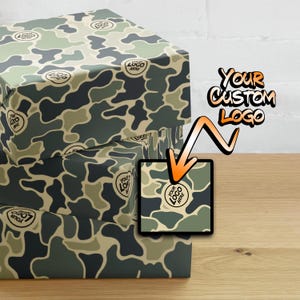 May include: Stack of gift wrap with a camouflage pattern. The pattern features green, brown, and tan colors. The text "YOUR CUSTOM LOGO" is written in a bold, black font on a white background.