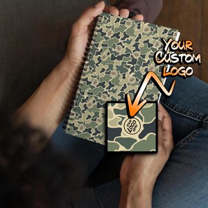 May include: A spiral bound notebook with a camouflage pattern. The notebook has a space for a custom logo. The text "Your Custom Logo" is written on the notebook.