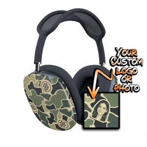 May include: Over-ear headphones featuring a dark green, tan, and black camouflage pattern on the ear cups. The cups display the text 'YOUR LOGO HERE' multiple times. An adjacent square graphic shows a person's portrait and 'YOUR CUSTOM LOGO OR PHOTO'.